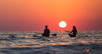 Man and woman on paddleboard at sunset