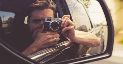 Man taking photo in rearview mirror in car