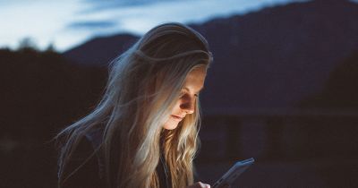 girl looking at phone in the dark with face lit up