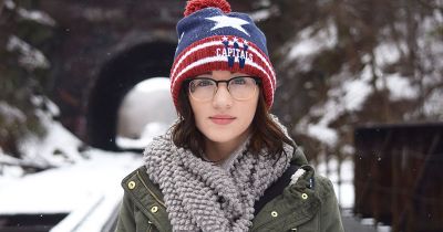 woman wearing winter hat surrounded by snow
