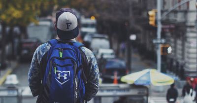 young man with backpack facing busy city street