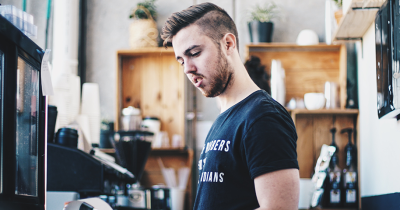 Man working behind the bar in a coffee shop, pulling espresso shots.