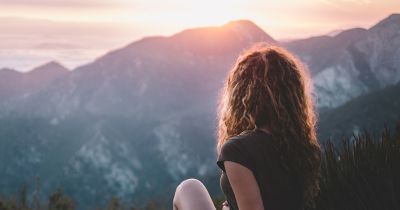 hip teen girl sitting on a rock at sunrise