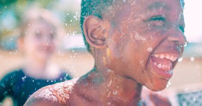 Little boy laughing while playing in water