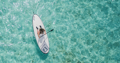 Aerial shot of woman paddleboarding in crystal clear water