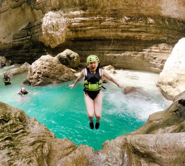 A girl jumping in the water canyoneering