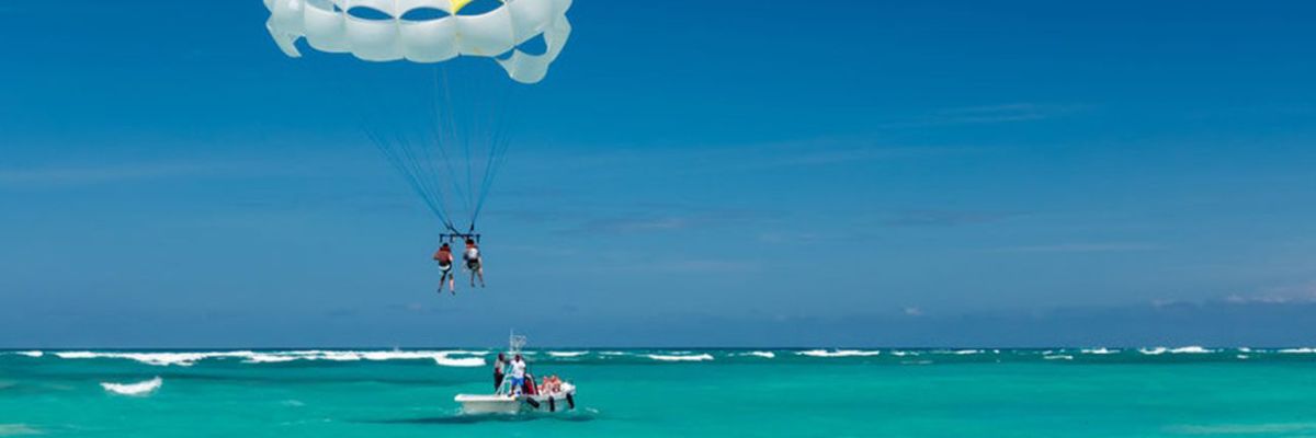 Two people parasail over turquoise ocean