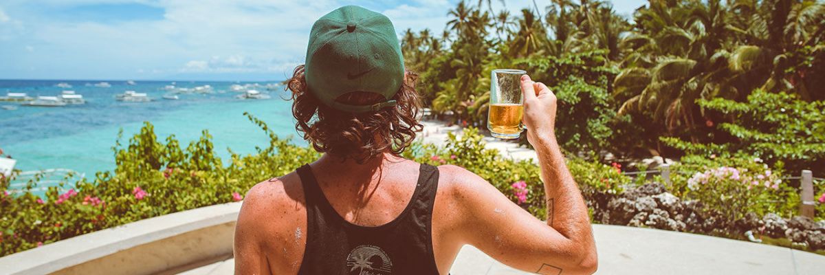 Surfer holding a glass of beer with his back on he camera