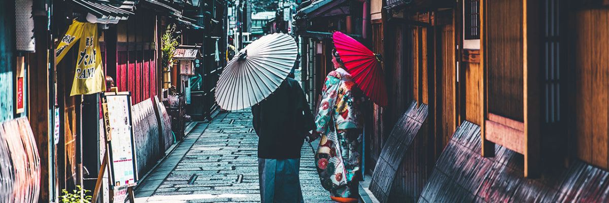 two people walking down a street in kyoto, japan