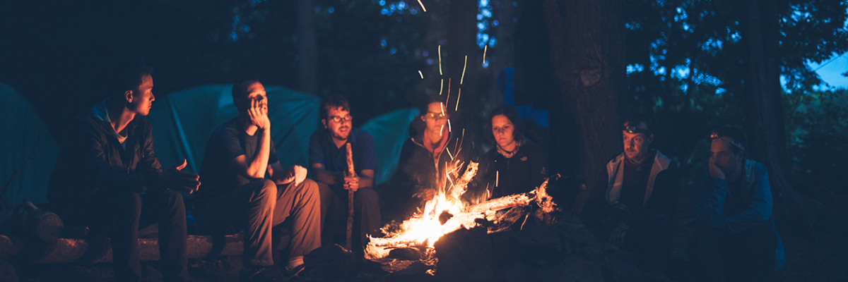 group of friends sitting around campfire