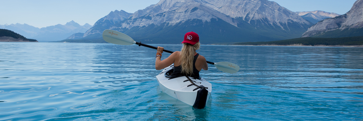 woman in red hat kayaking in crystal blue water