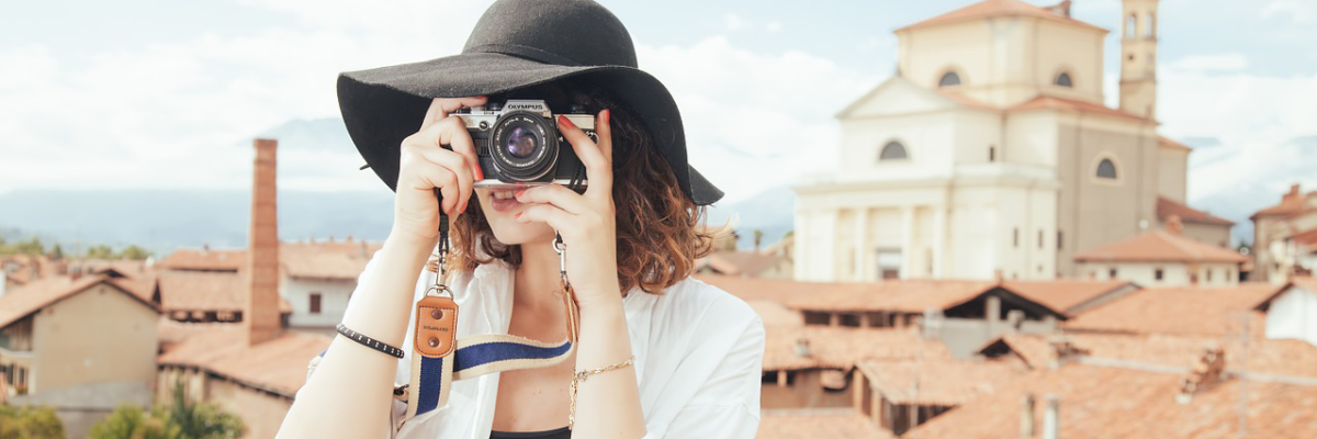 woman in black hat snapping a photo with a film camera