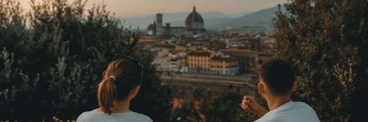 two people sitting near green trees overlooking Florence architecture in the background