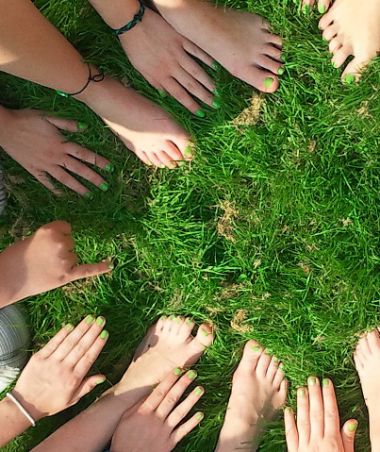 Circle of people with their hands in the grass