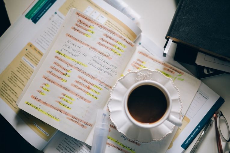 a notebook with spanish notes with a cup of coffee to the side