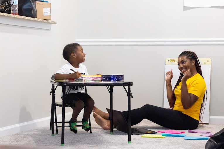 person sitting on floor in front of child sitting at desk