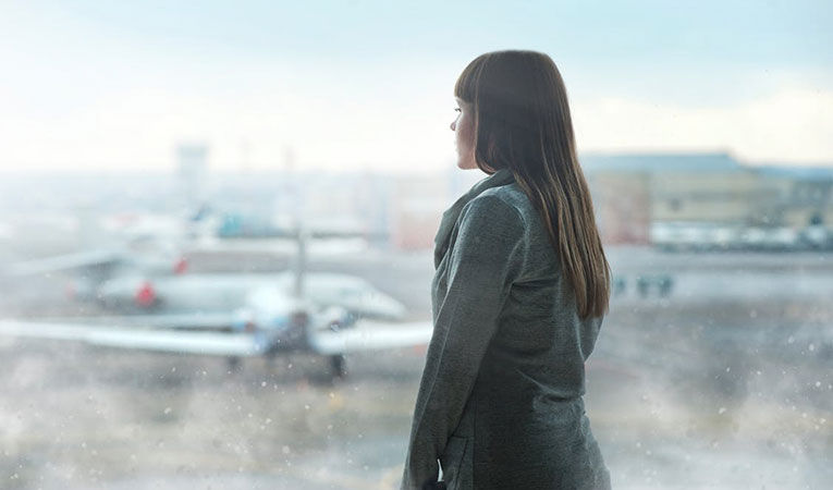 Woman at the airport looking out window towards the airplanes