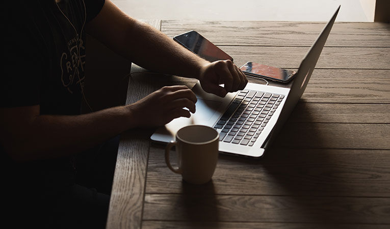 Person sitting at a computer with a coffee cup