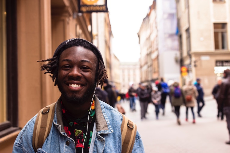 smiling person with headphones in front of blurred Stockholm street