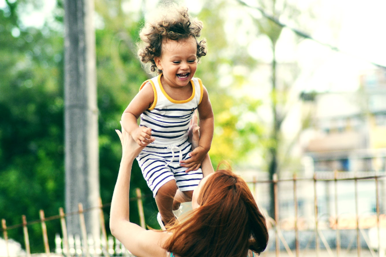 person holding smiling child in the air