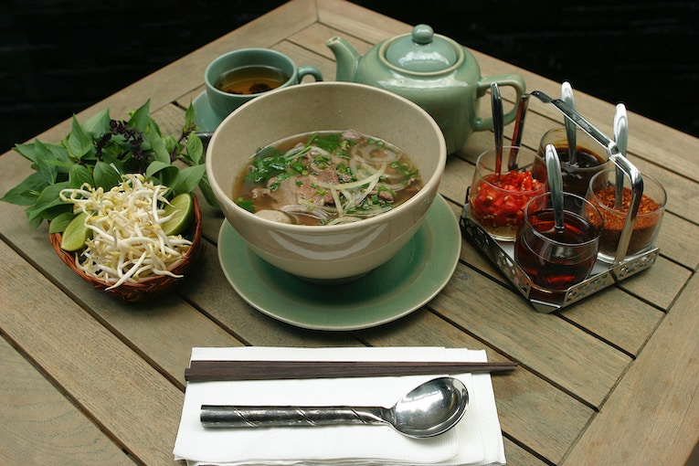 vietnamese pho in a bowl on a tabletop with condiments