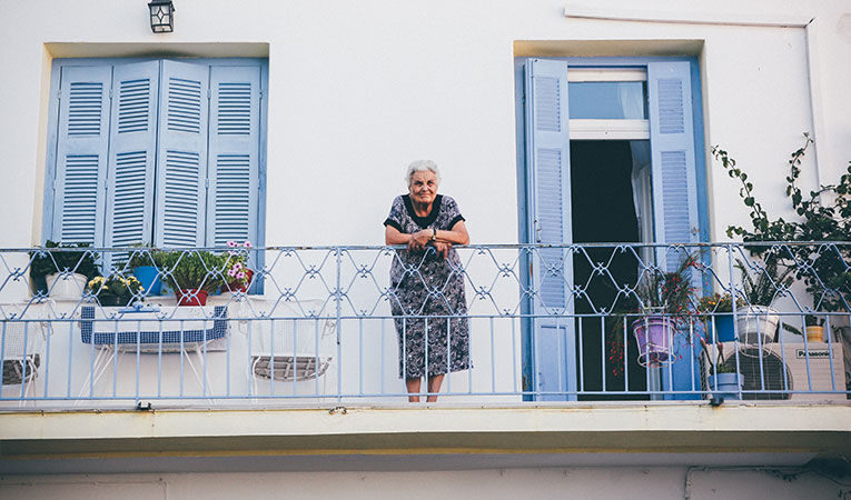 Old woman looking over balcony in greece