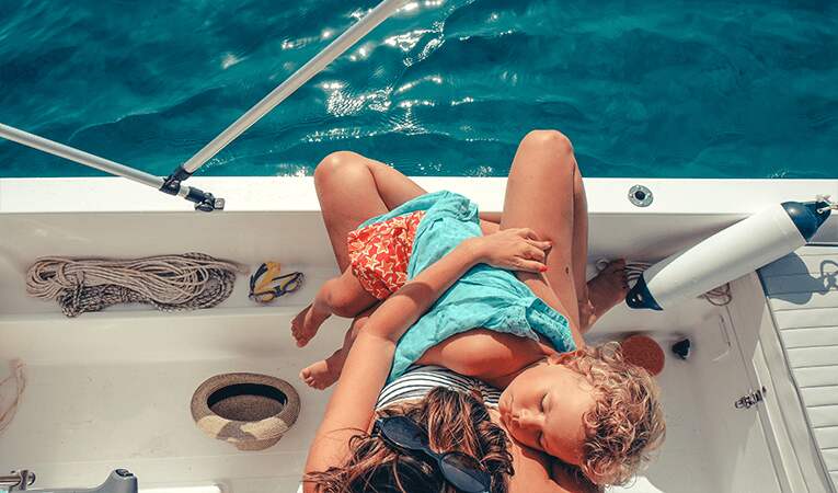 Woman holding sleeping child on boat