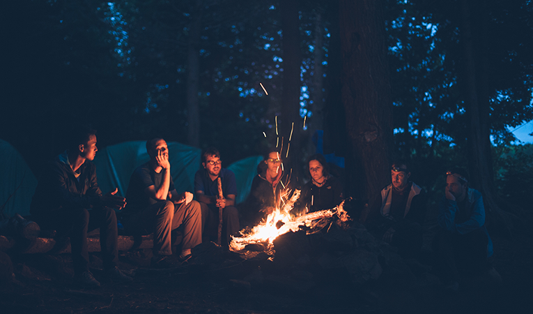 group of friends sitting around campfire