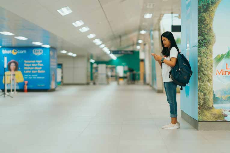 person holding backpack looking at smartphone