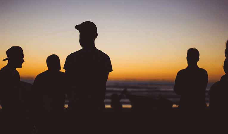 Silhouette of teen boys hanging out at sunset