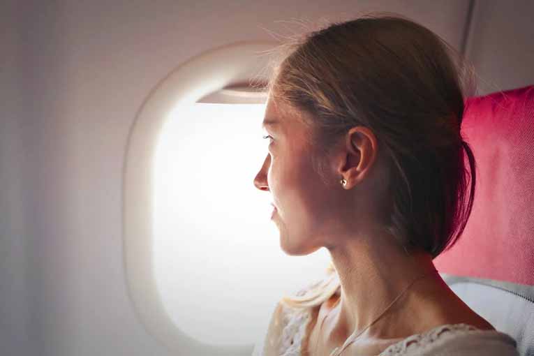 Traveler happily staring out an airplane window