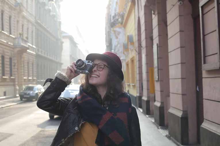 Traveler walking down a city street taking photos with a camera