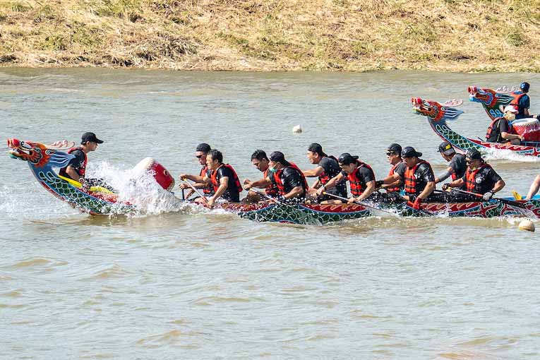 group of people riding on boats shaped like dragons in water