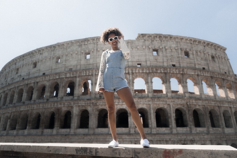person wearing sunglasses smiling in front of Colosseum in Rome