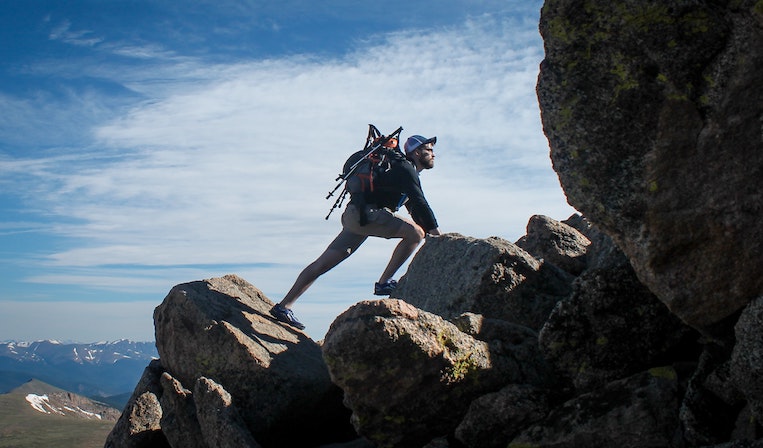 traveler climbing up a mountain while wearing a large backpack