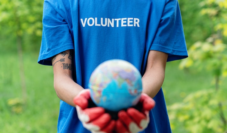 person in a blue volunteer shirt holding a small globe
