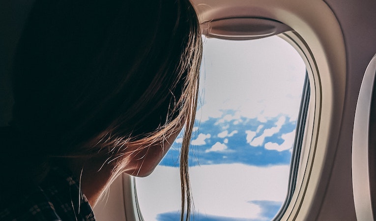 person holding a phone and looking out airplane window