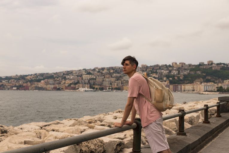 person leaning on an ocean barrier looking afar