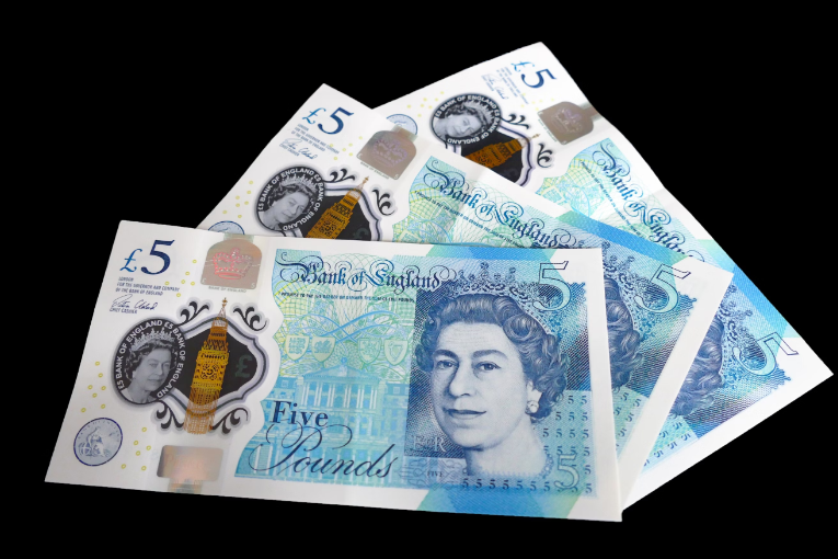 three british 5 pound bank notes on black background