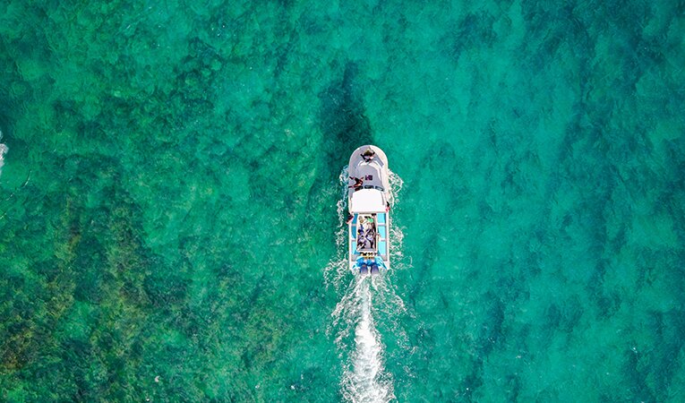 aerial shot of boat across crystal clear water
