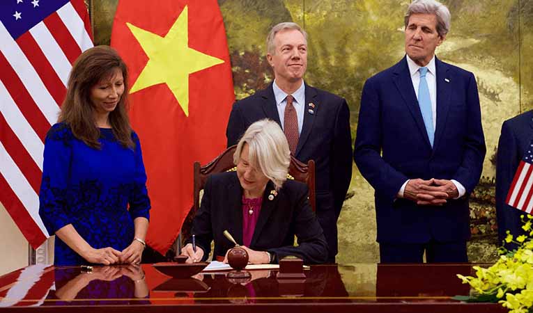 peace corps director and (former) secretary of state John Kerry signing document with ambassadors to Vietnam in Hanoi