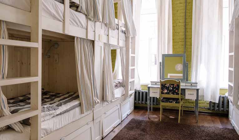 rows of empty bunk beds in a green room with a vanity mirror