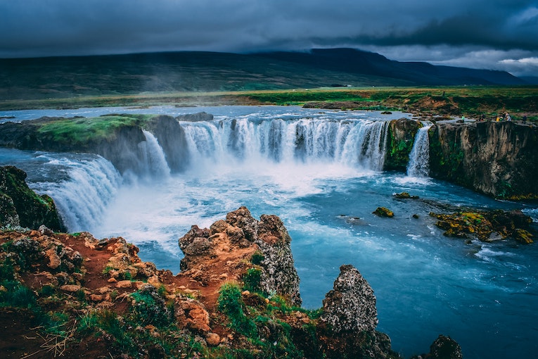 A large flowing waterfall running over moss covered rocks in Iceland 