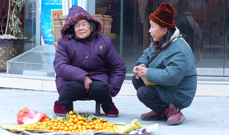 Chinese women chatting at an orange vendor