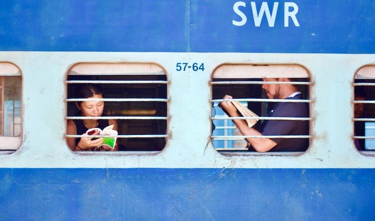 two travelers reading books on an open air train