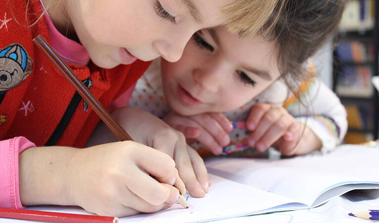 Two little girls writing in a workbook
