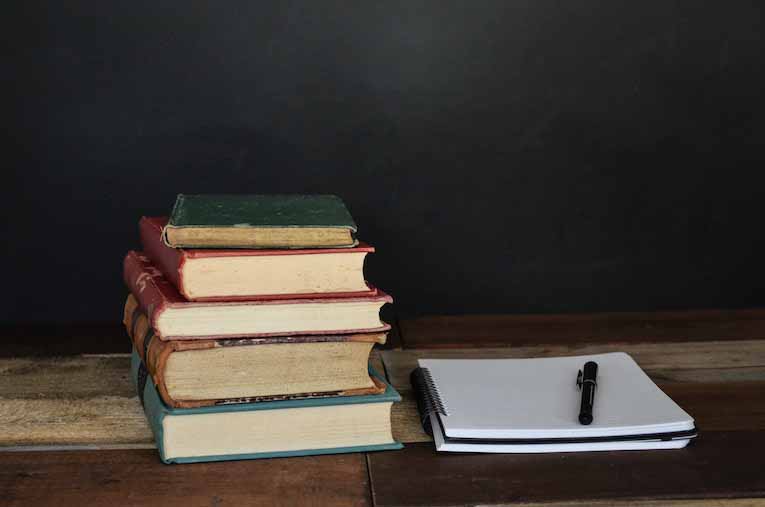 stack of books next to paper and pen