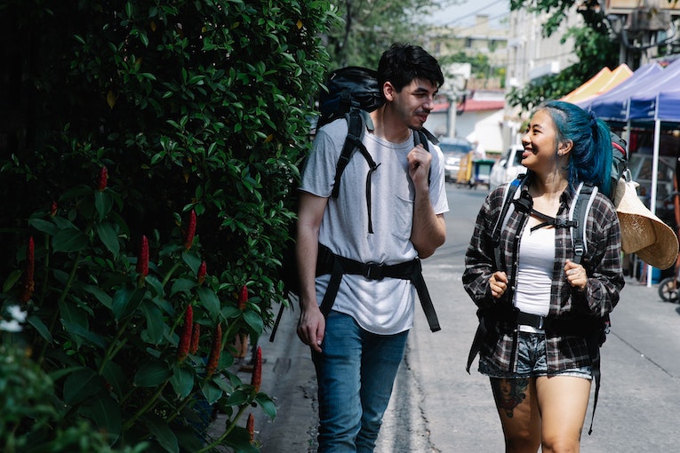 two backpackers walking down a street and smiling