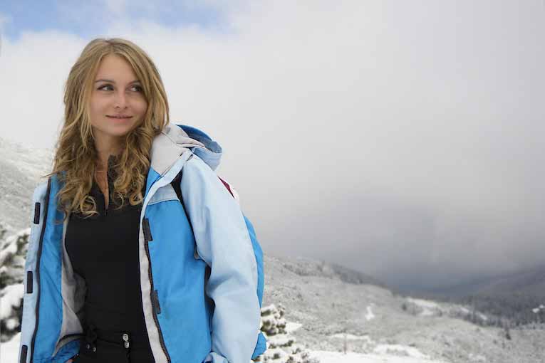 A traveler wearing a blue and white jacket traversing a snowy landscape