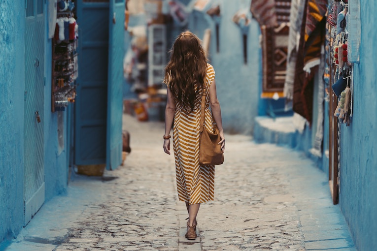 traveler in a yellow dress wandering down a street in chefchaouen morroco